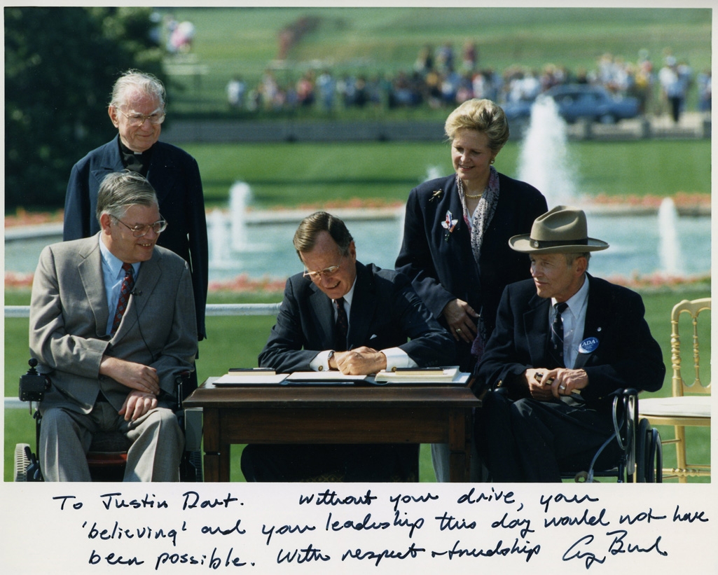 56942be9feb451344a7c1600_Photo_of_President_George_H._W._Bush_signing_the_Americans_with_Disabilities_Act_inscribed_to_Justin_Dart,_Jr.,_1990