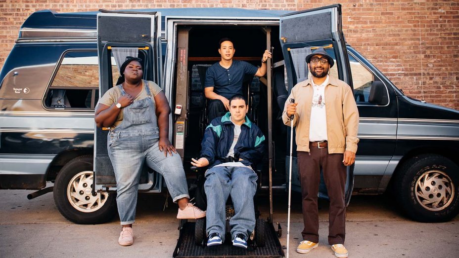 The stars of COME AS YOU ARE: Gabourey Sidibe (wearing overalls), Grant Rosenmeyer (in a blue and light blue jacket; in a wheelchair; on a ramp), Hayden Szeto (wearing a dark blue top; in a wheelchair; on a ramp), and Ravi Patel (in a light tan jacket, white shirt, and red jeans, holding a walker; on a ramp) posting in front of a van